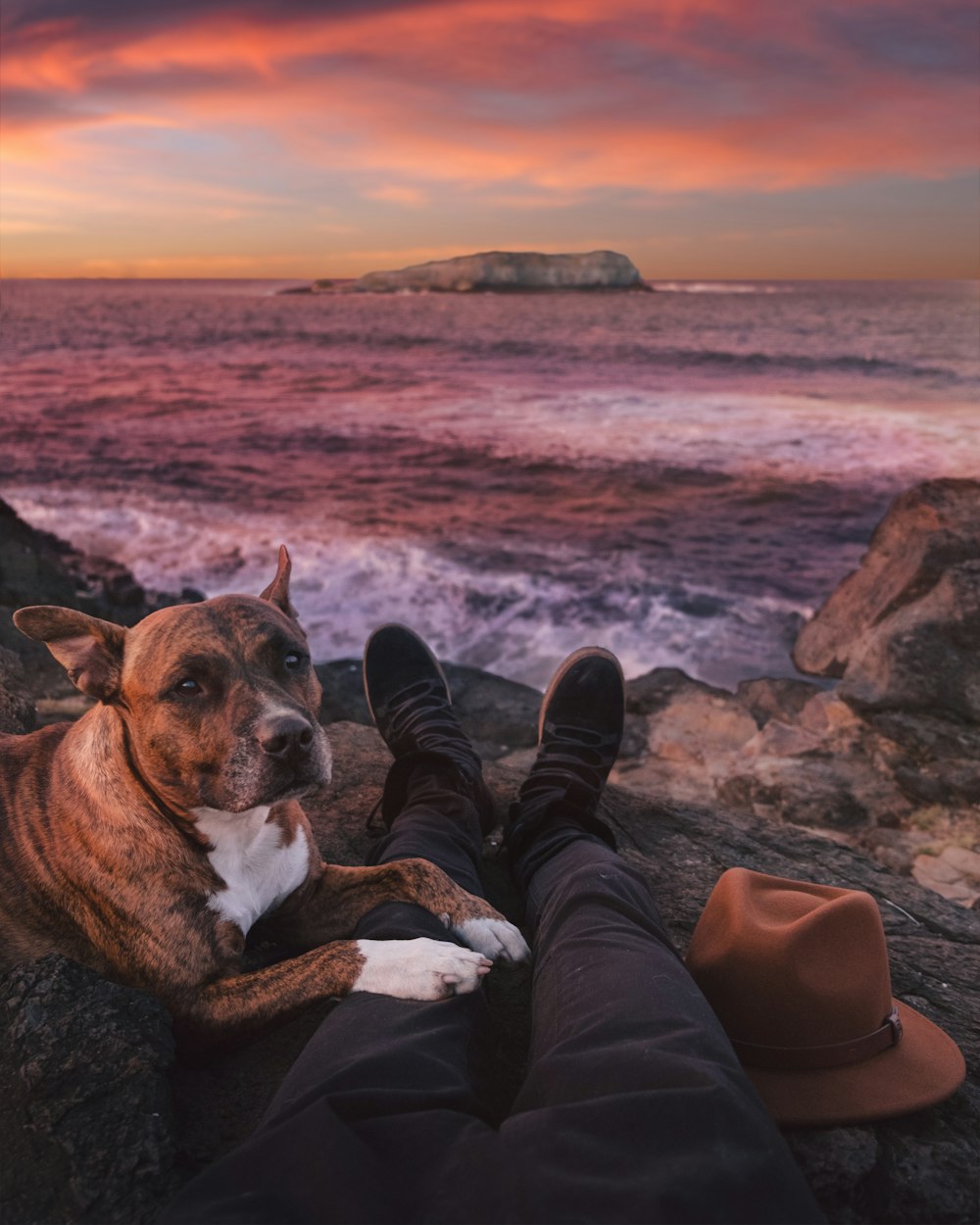 person sitting on rock beside of brindle through sea waves crashing on rock