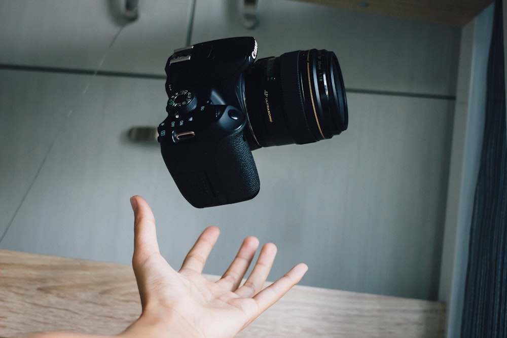 Fotocamera DSLR nera su tavolo di legno marrone