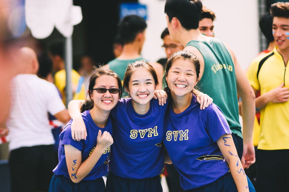 Group of female students excitedly smiling at the camera during a sports event
