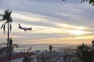 An airplane flying over a stunning coastline at sunset.