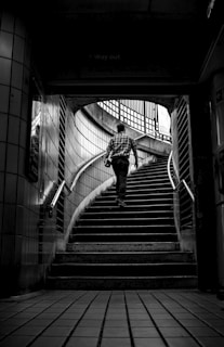 grayscale photo of man walking upstairs