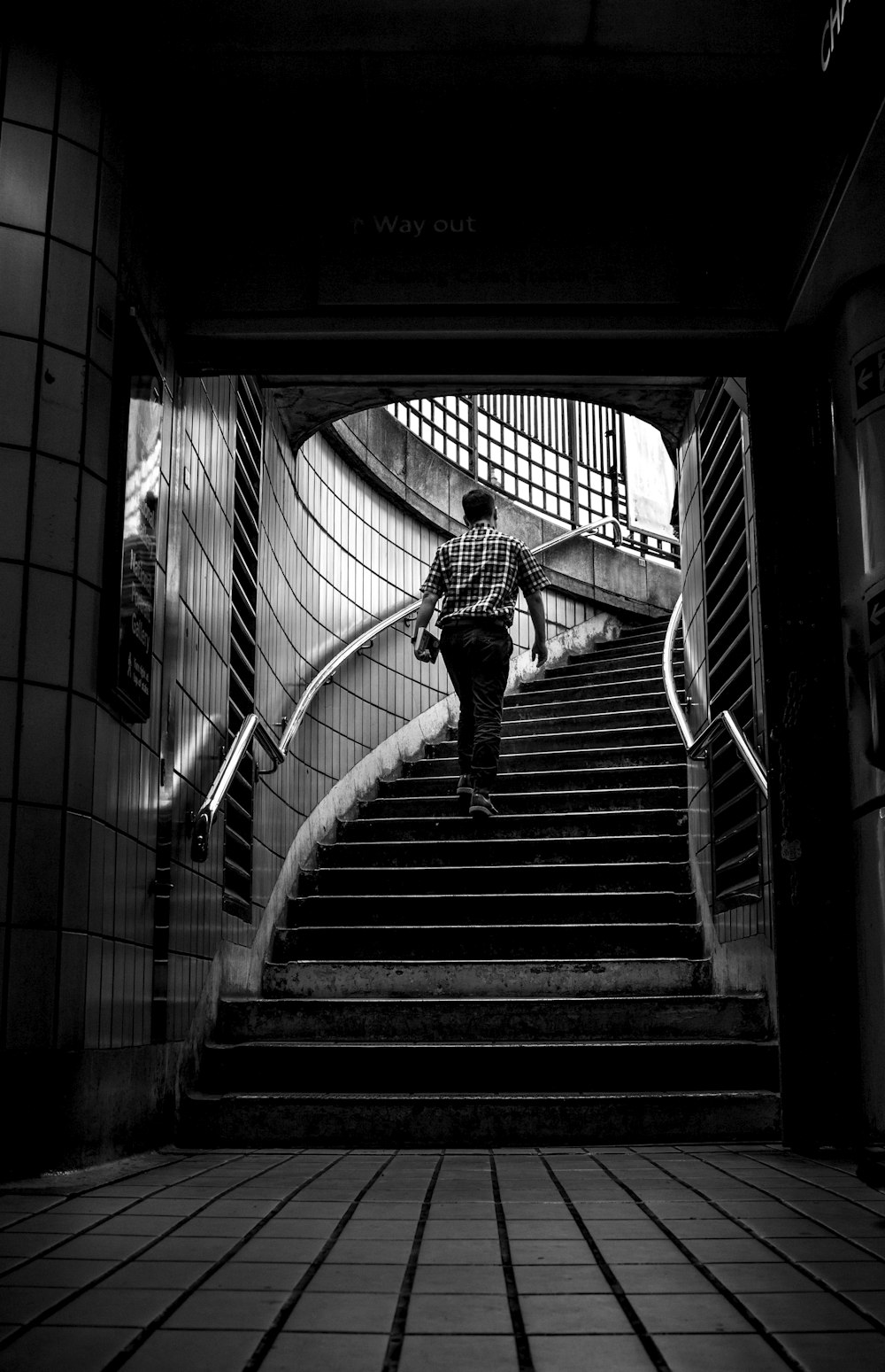 grayscale photo of man walking upstairs