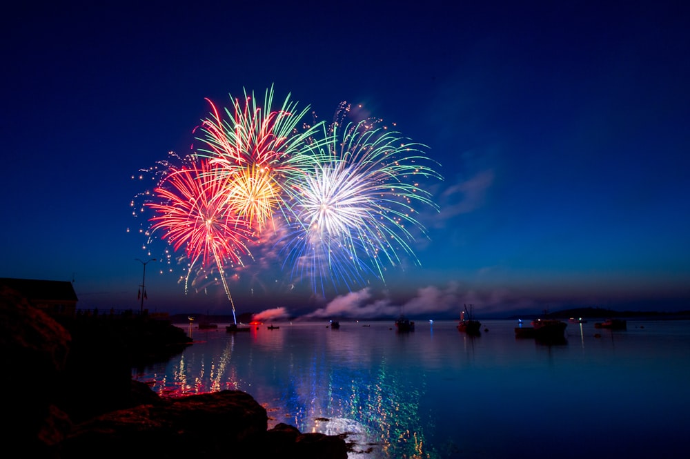 Fireworks explode in bright colours over a lake