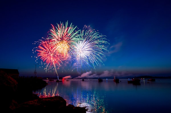 Fireworks explode in bright colours over a lake