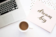 A warm, inviting workspace with a notebook, coffee cup, and a laptop displaying a blog about personal growth.