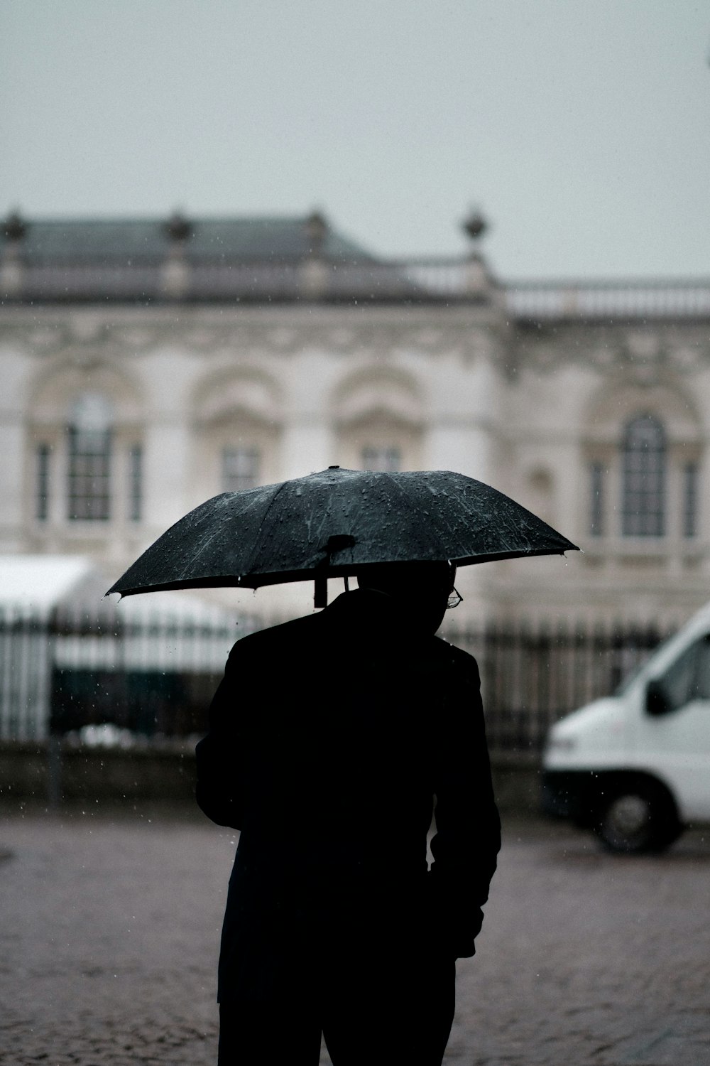 pessoa segurando guarda-chuva preto em pé perto do veículo branco