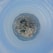 A tiny planet effect transforms a panoramic cityscape into a spherical view. The densely packed buildings and skyscrapers encircle a central point, creating a miniature world of urban architecture. A section of water and hills surrounds the city, adding natural elements to the scene.