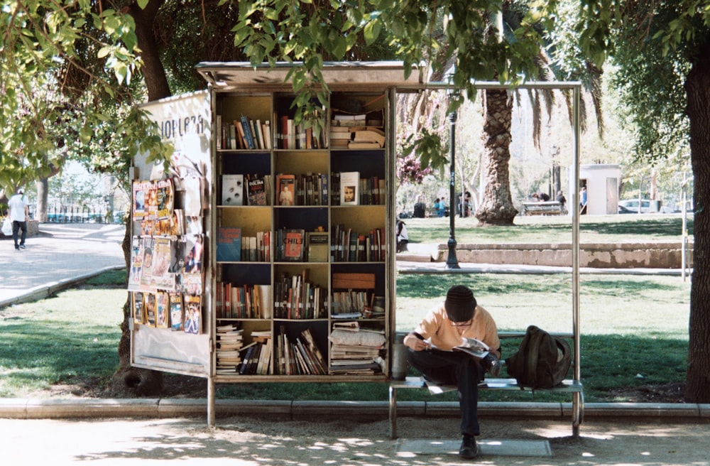 boy sitting on bench beside bookshelf