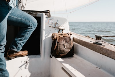 person in blue denim jeans on yacht beside brown bag daring zoom background