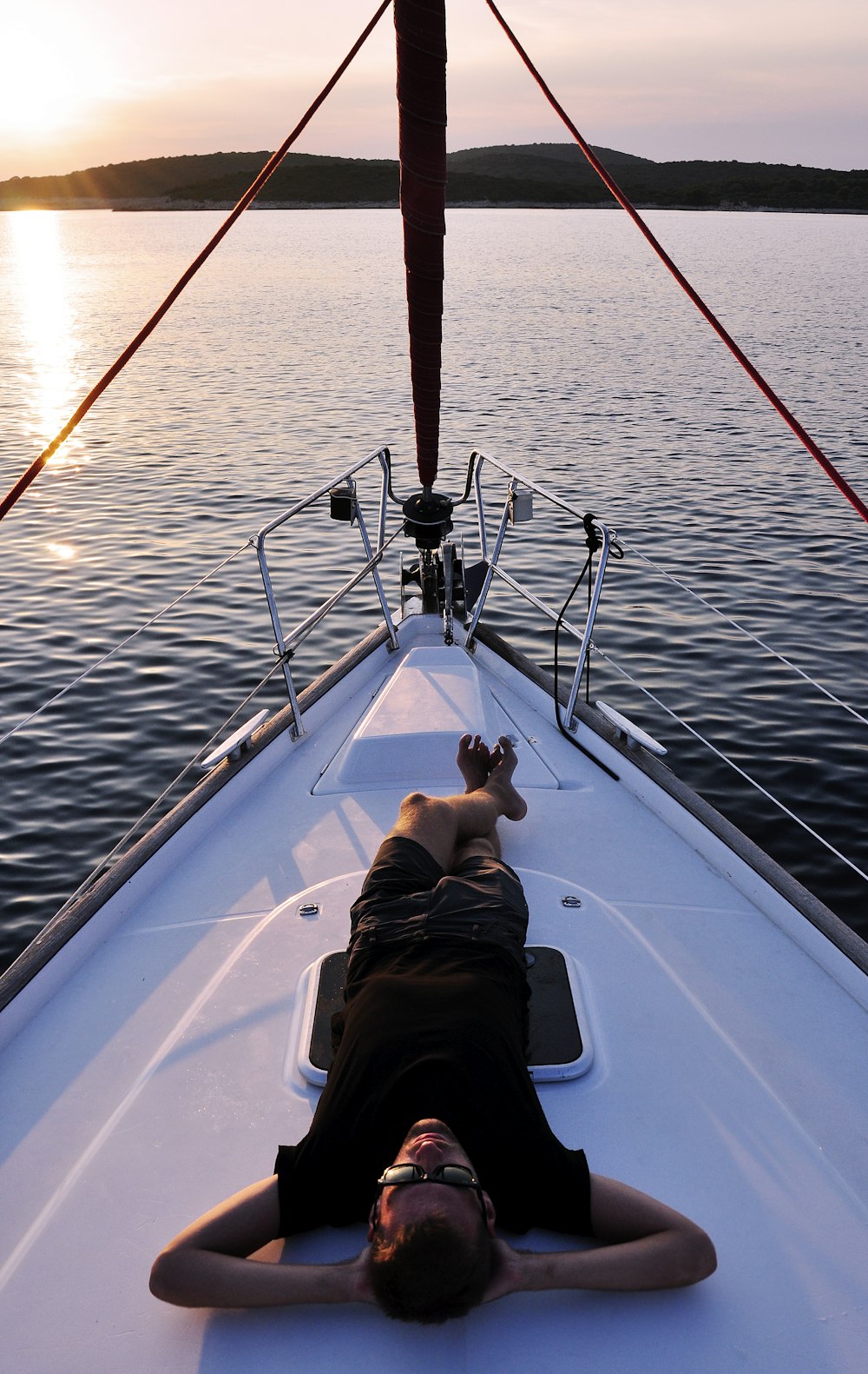 man lying on white boat