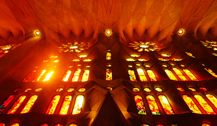Sunlit church interior with colorful stained glass windows casting lively patterns on the walls.