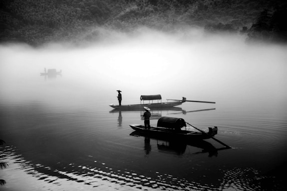 A serene photo of a traditional Vietnamese boat gliding through the misty waters of Halong Bay at sunrise.