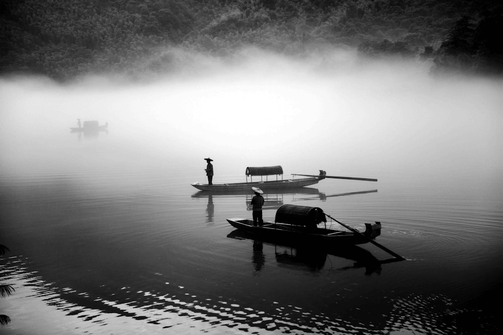 foto em tons de cinza de dois barcos a remo