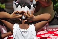 A joyful child wearing a paper crown, smiling with a backdrop of craft supplies.