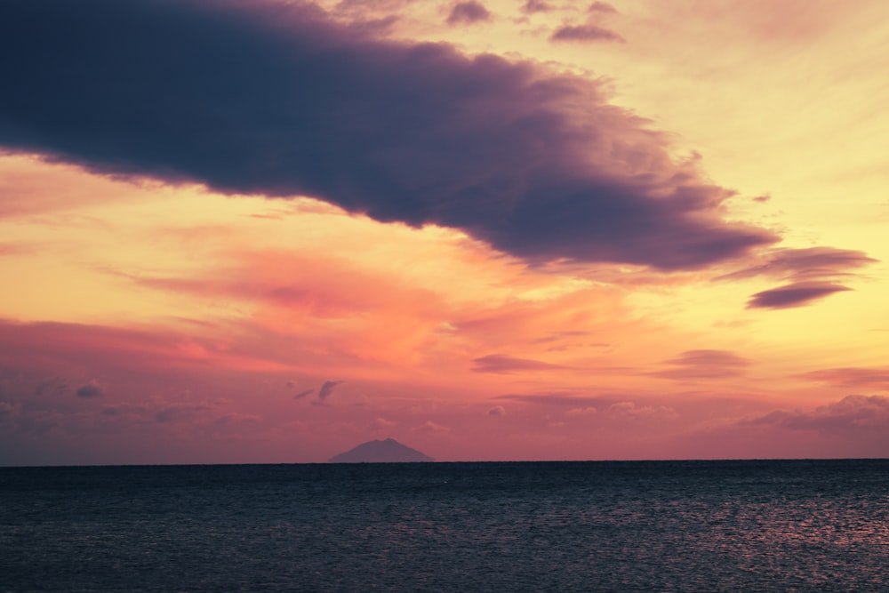 body of water under cloudy sky during sunset