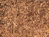 A close-up view of a pile of wood chips, displaying various sizes of shredded wood pieces in shades of brown.