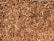 A close-up view of a pile of wood chips, displaying various sizes of shredded wood pieces in shades of brown.