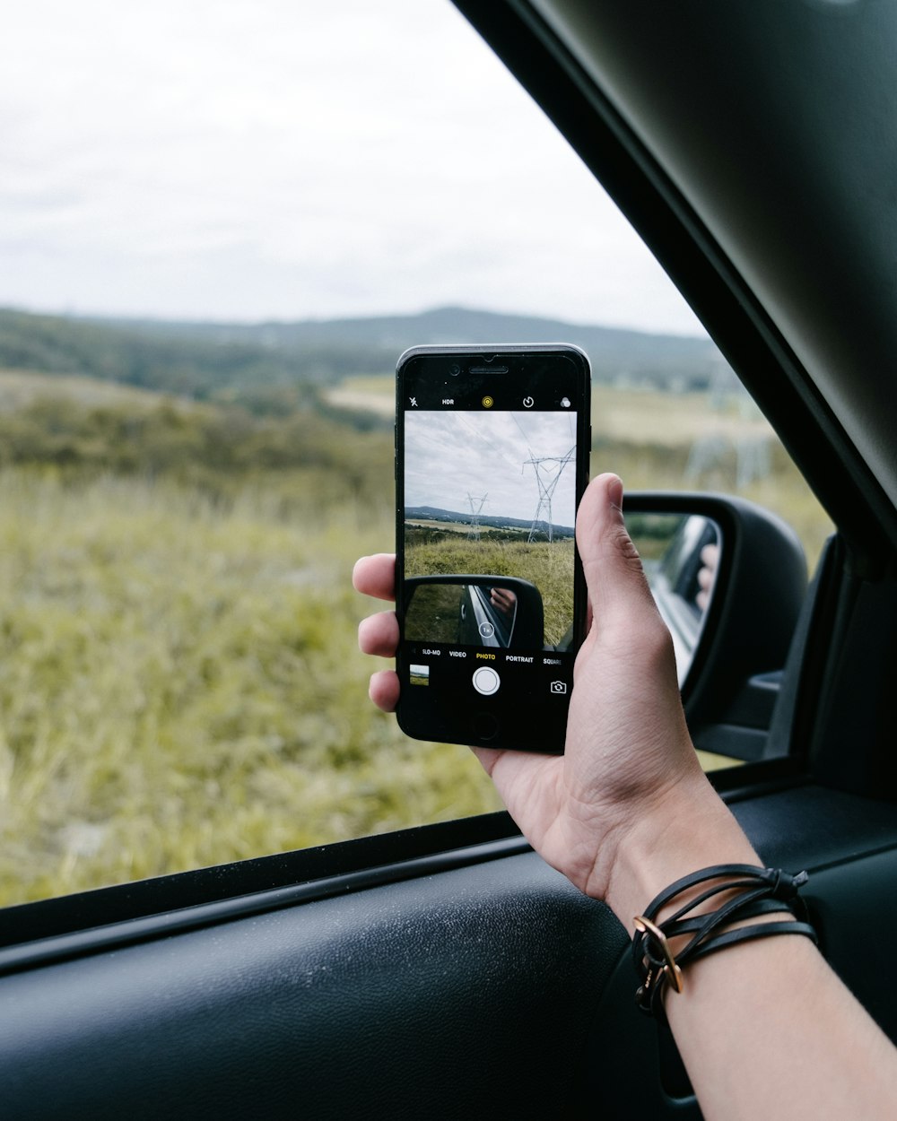 Une personne prenant une photo par la fenêtre de sa voiture avec son smartphone.