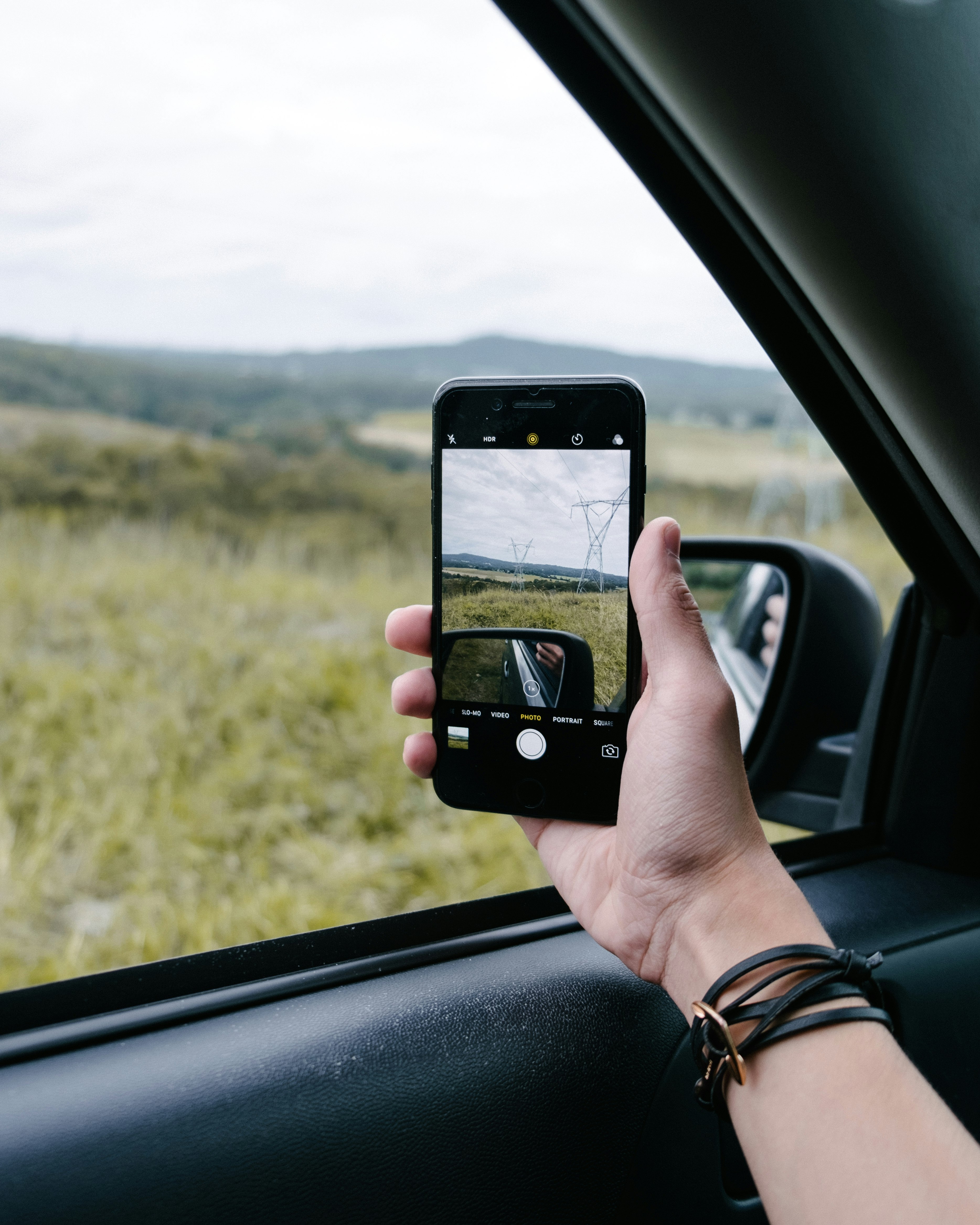 A person taking a picture out their car window with their smartphone.