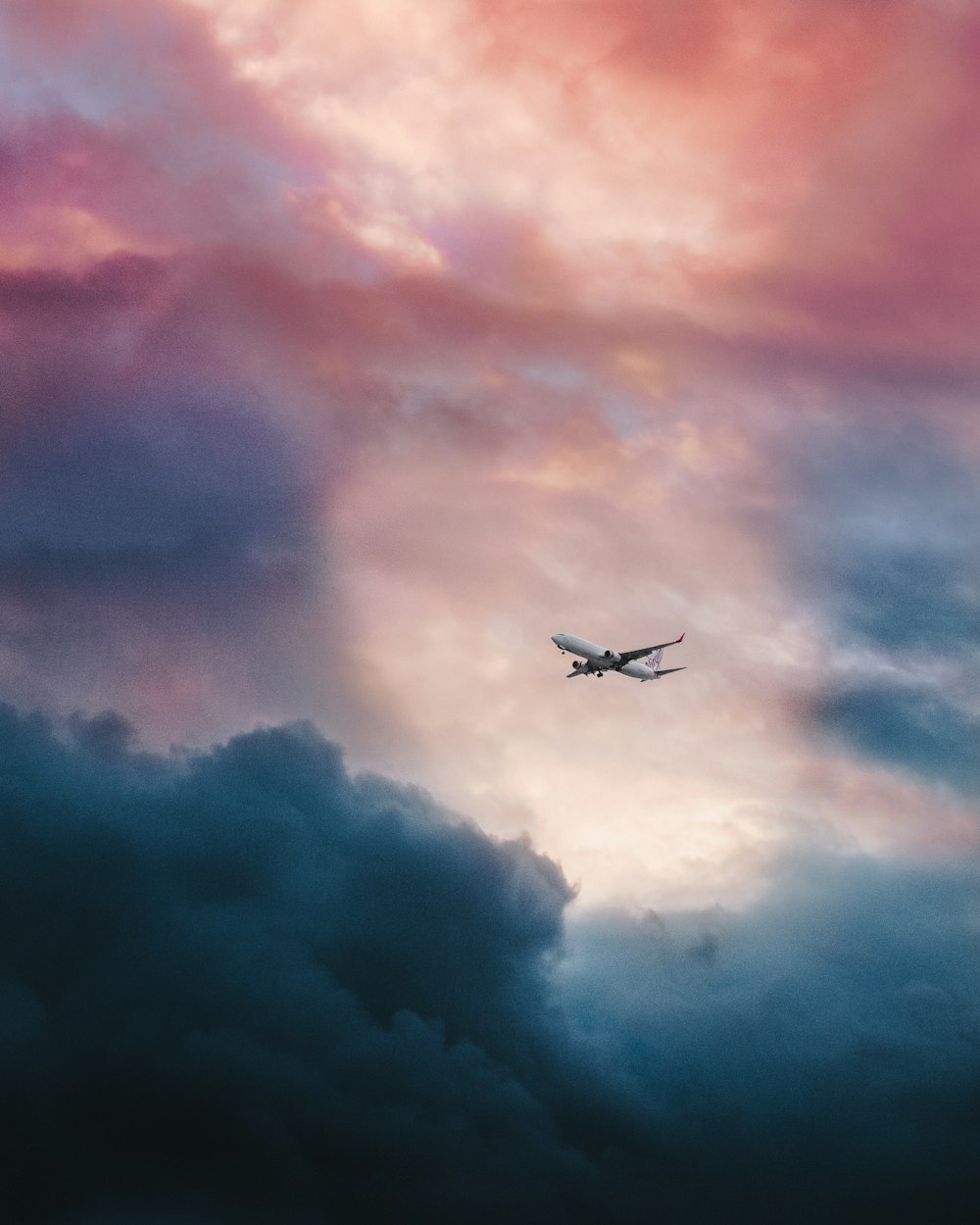 회색 구름 위를 날고 있는 하얀 비행기