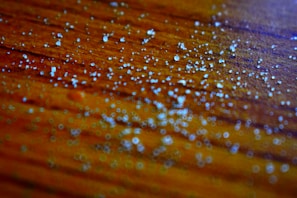 Close-up of golden biomass pellets spilling gently from a rustic wooden scoop on a warm beige background