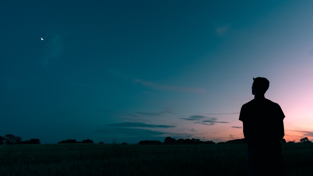 Silueta del hombre que mira la estrella durante la puesta del sol