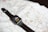 A smartwatch with a black band is resting on an unfolded map. The smartwatch screen displays a cartoon character pointing at the clock hands.