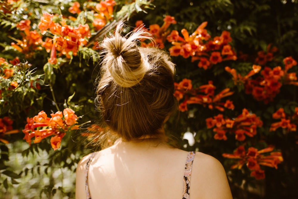 woman in white sleeveless dress standing near red flowers