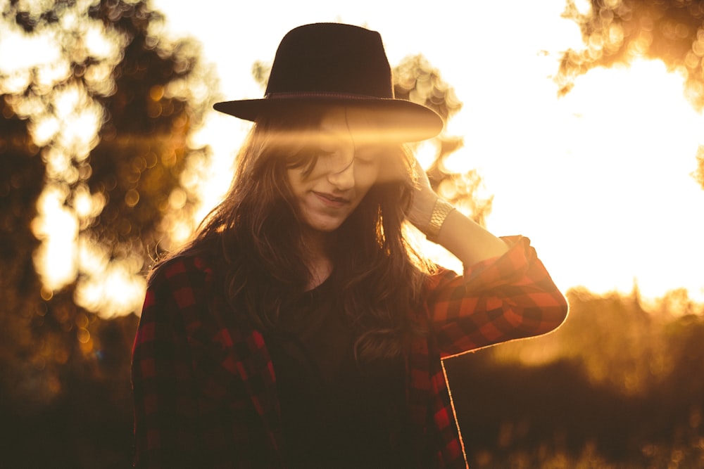 woman wearing red and black checked top and black hat