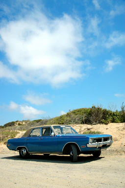 A vintage car parked beside a rustic roadside café under a clear blue sky.