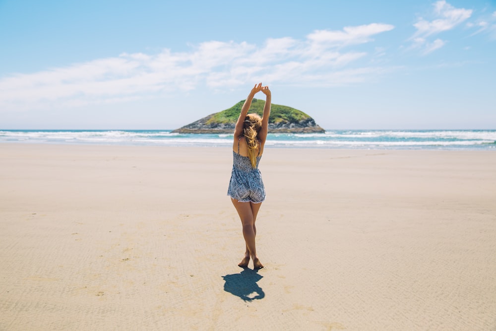 Young woman stretching on a sand beach with an island in the background in Tofino
