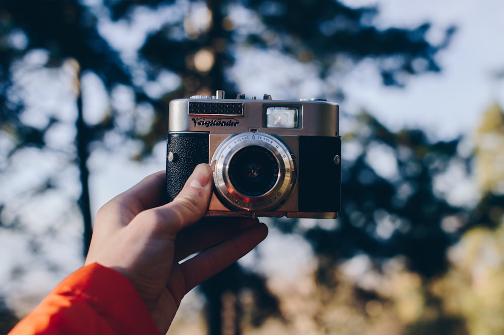 person holding black and gray point-and-shoot camera