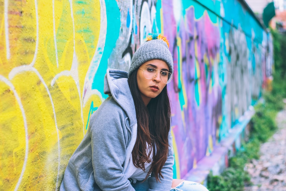 woman leaning beside wall during daytime