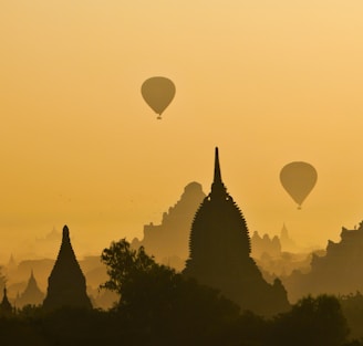 silhouette of two hot air balloons near temple