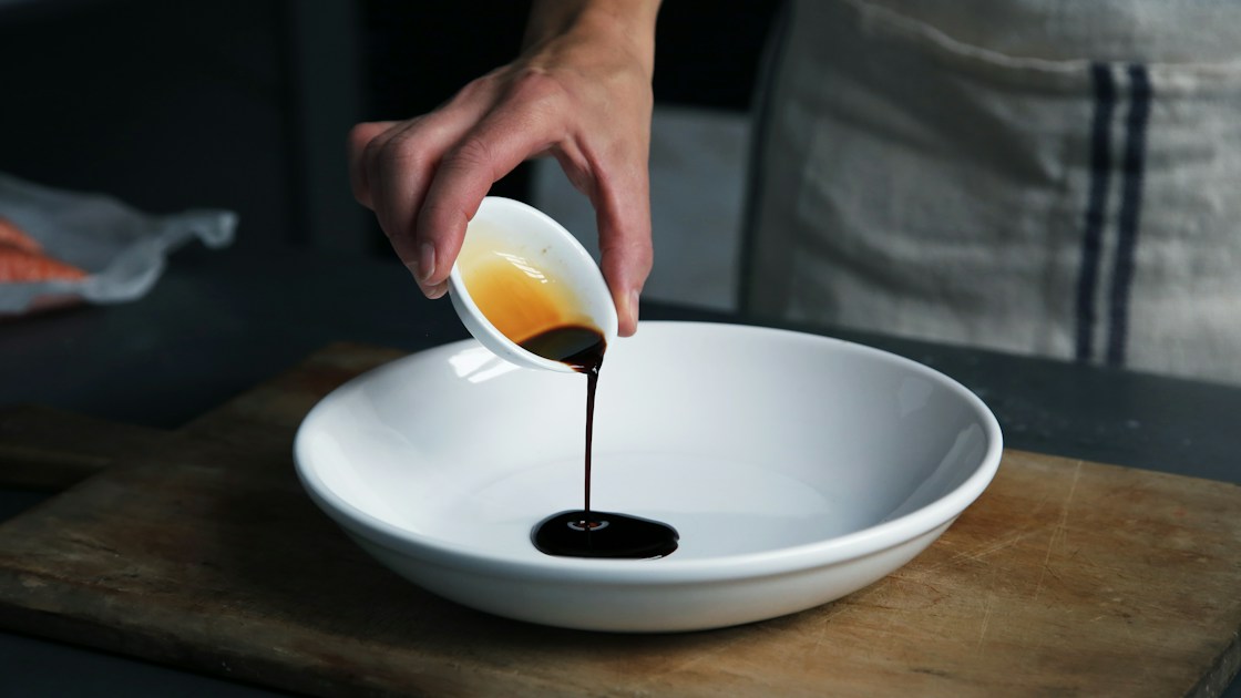 Vinaigre balsamique de Modène versé d'une coupelle dans une assiette blanche