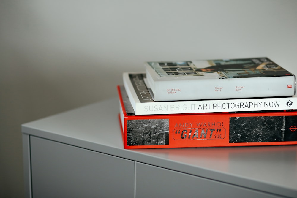 stacked three assorted books on gray wooden surface