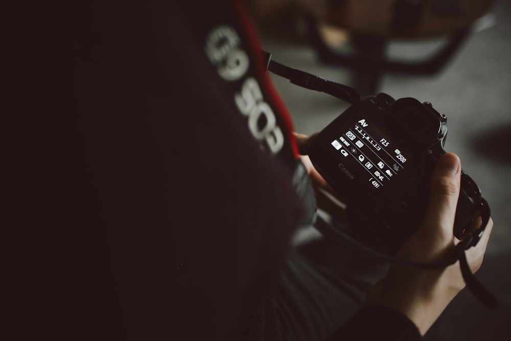 persona sosteniendo una cámara DSLR negra