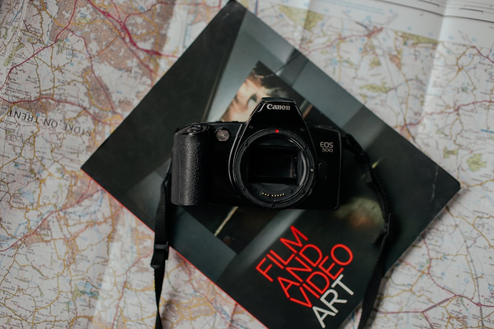 fotocamera reflex digitale Canon nera in cima al libro nero