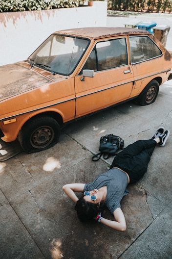 woman lying near the orange vehicle