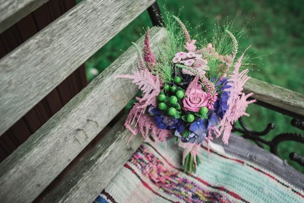 Bright, colorful flower seeds spilling out of a rustic paper bag onto a garden bench.