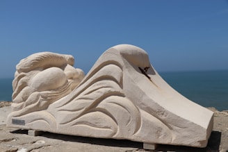 Custom-made cement sculpture inspired by ocean waves, displayed on a sandy surface.