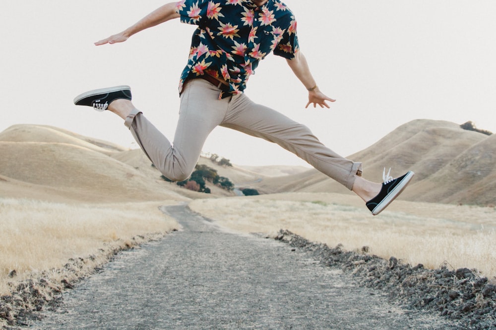 uomo in camicia nera e pantaloni grigi che salta