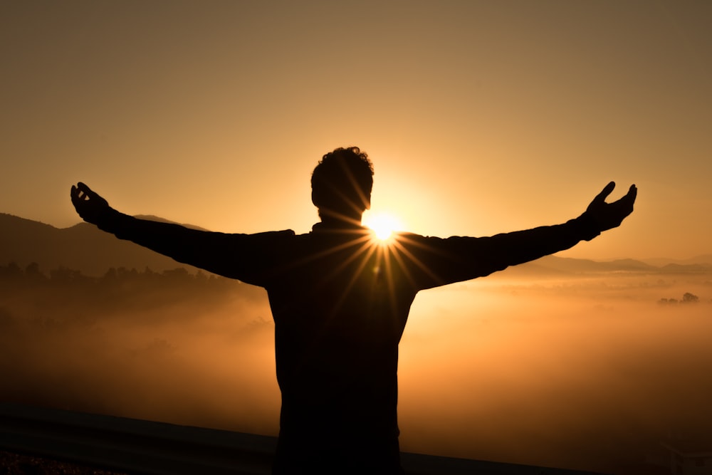 A man standing with a feeling of security wailing his arms out, silhouetted in a Chiang Mai sunrise