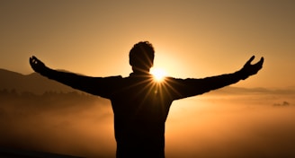 silhouette photo of man on cliff during sunset