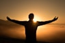 silhouette photo of man on cliff during sunset