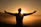 silhouette photo of man on cliff during sunset