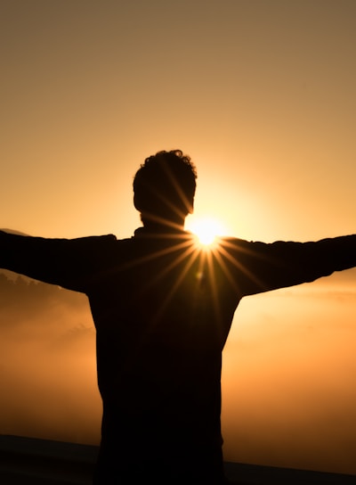 silhouette photo of man on cliff during sunset