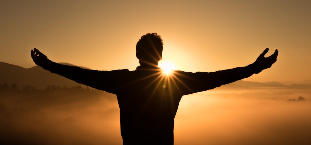 silhouette photo of man on cliff during sunset