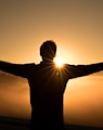 silhouette photo of man on cliff during sunset