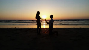 Sunset silhouette of a couple holding hands on a quiet beach.